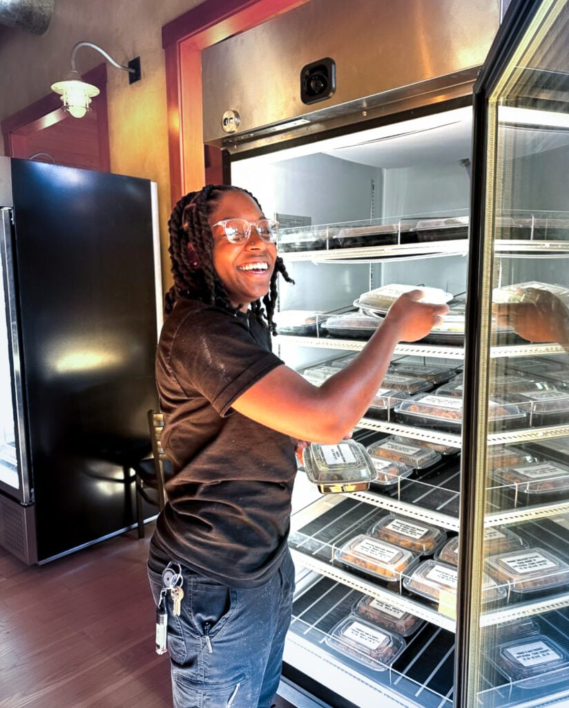 smiling girl pulling fresh meals out of a healthy food vending machine.